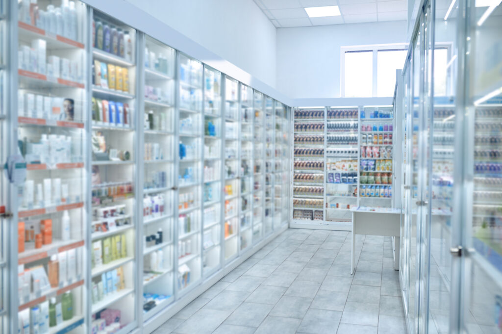 Drugstore furnished with numerous glass display cabinets filled with different pharmaceutical drugs and beauty products